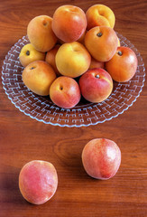 Fresh ripe apricots on plate on wooden background closeup