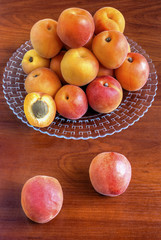 Fresh ripe apricots on plate on wooden background closeup