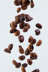 Falling grains of roasted coffee on a white background