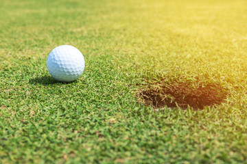 White golf ball on green near hole