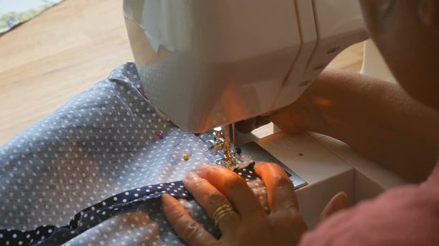 expert female hands using sewing machine stitching fabric together to make arts and crafts bag in studio