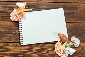 Shells and notepad on wooden table. Top view with copy space