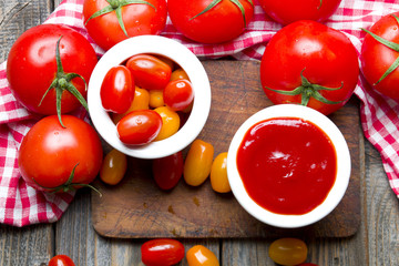 Ketchup with tomatoes on wooden background