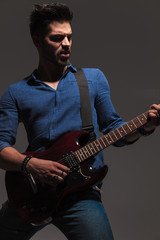 passionate young guitarist playing his electric guitar
