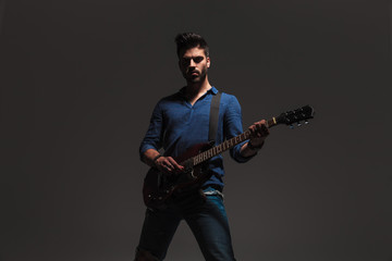 young man standing and playing electric guitar