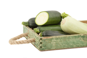 Green fresh zucchini in the wooden tray, isolated