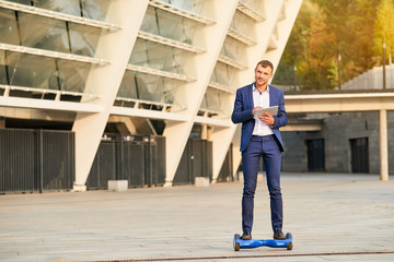 Businessman with tablet on hoverboard. Young man in the street.