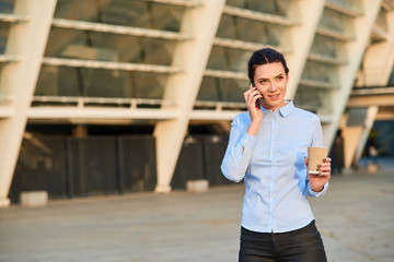 Businesswoman holding phone and cup. Young caucasian female. Telephone etiquette tips.