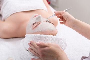 Obraz na płótnie Canvas Woman gets face mask by beautician at spa