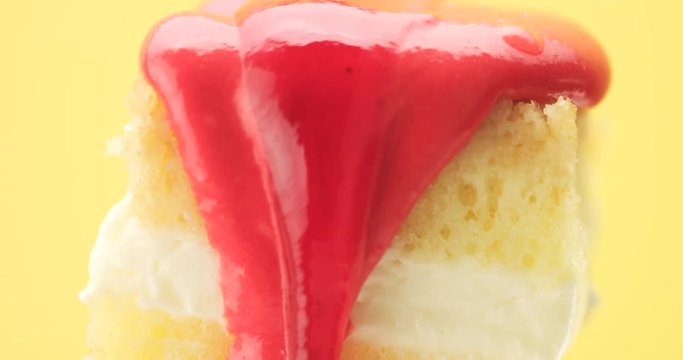 lemon cake slice on a fork with a cream and fruit topping pouring on