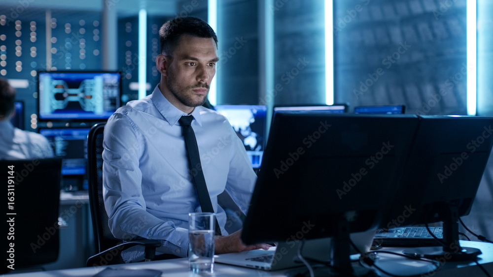 Poster Professional Technical Controller with Colleagues at Their Workstations. They're in Monitoring Room with Multiple Displays Surrounding Them.