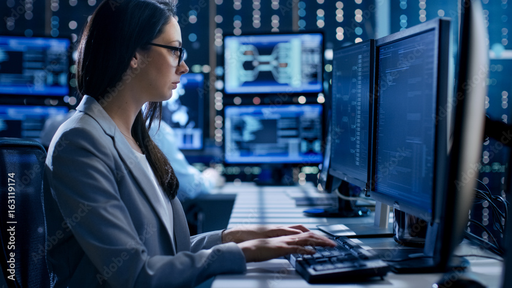 Leinwandbilder Female Engineer Controller Observes Working of the System. In the Background People Working and Monitors Show Various Information.
