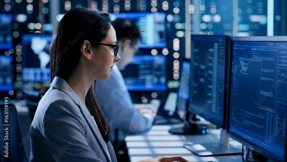 Leinwandbilder Female Engineer Controller Observes Working of the System. In the Background People Working and Monitors Show Various Information.