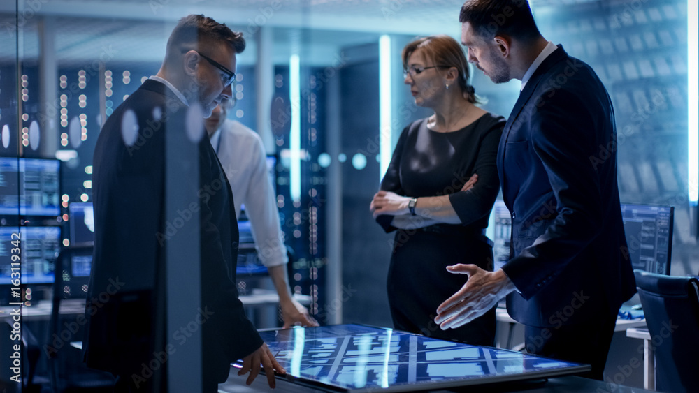 Poster Team of Government Agents Having Meeting with Help of Touchscreen Interactive Table in State of the Art Monitoring Room Full of Computers with Animated Screens.
