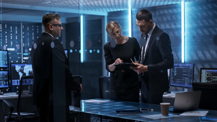 Team of Chief Engineers Have Emergency Meeting in System Controls Center. They Consult Data on Tablet Computer and Analyse it. Computers in the Room Have Various Information on Their Screens.