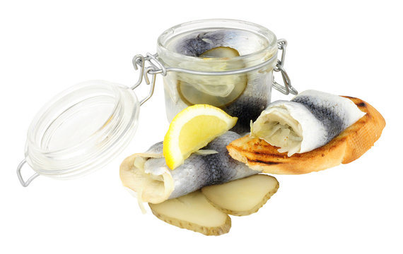 Pickled rollmop herrings in a glass storage jar and toasted bread isolated on a white background