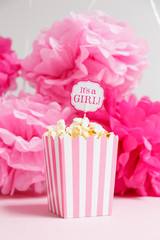 It's a girl sign in a popcorn bag at the baby shower party.  Paper flowers background.  Baby shower celebration concept