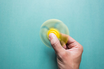 Yellow fidget spinner in hand rotates - obrazy, fototapety, plakaty