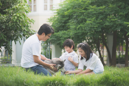 Happy Asian Family Playing With Siberian Husky Dog