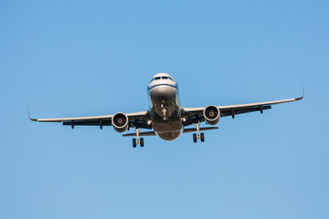 Passenger aircraft in flight with landing gear released on blue sky background