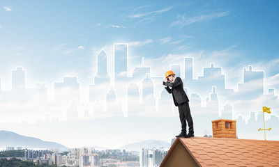 Engineer man standing on roof and looking in binoculars. Mixed media