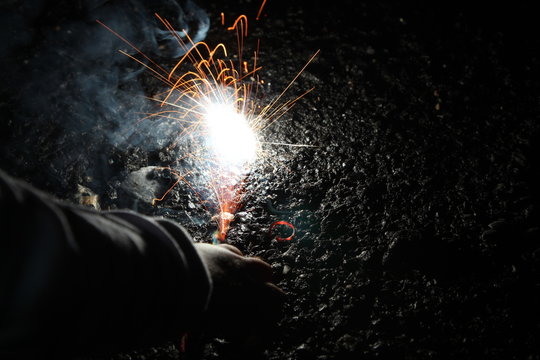 A child playing with burning sparkler firework. Motion blur effect over black background. Selected Focus. Light trail