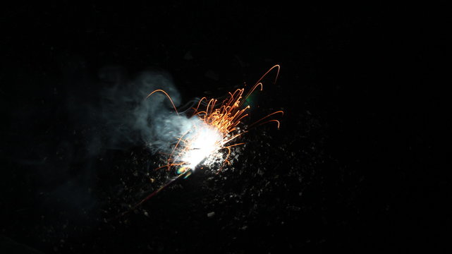 A child playing with burning sparkler firework. Motion blur effect over black background. Selected Focus. Light trail