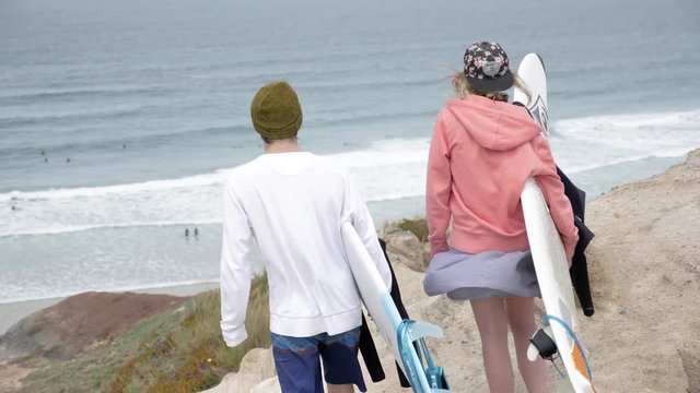 Surfers walking on a cliff to check the surf spot. Slowmotion footage in 4k quality.