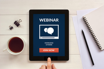 Webinar concept on tablet screen with office objects on white wooden table. All screen content is...