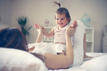 Fototapeta premium Mother and baby playing in the bed.