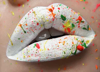 Kreatives Make-up-Thema Makro und Nahaufnahme: Schöne pralle Lippen mit weißer Farbe und farbigen Sprays © Alex