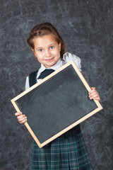 Portrait of happy little schoolchild on background of backboard in school, indoor.