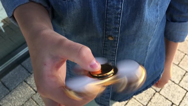 Gold fidget spinner in hand. Popular trendy toy close-up.
