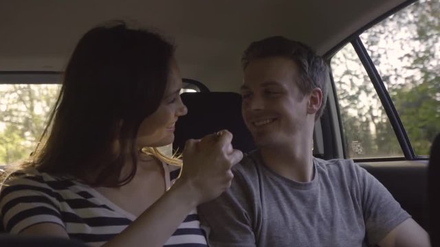 Playful Couple Throw Apples In The Air And Catch Them, In The Back Seat Of Moving Car (Slow Motion)