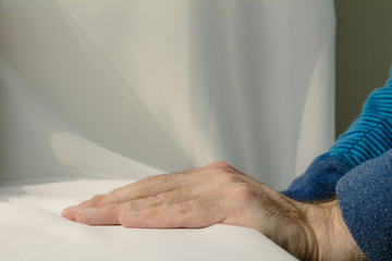 Man leaning and puts his hands down on white cloth background