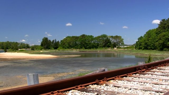 Railroad tracks running along beautiful coast of Cape Cod passing sandbars, inlet coves and wooded headlands