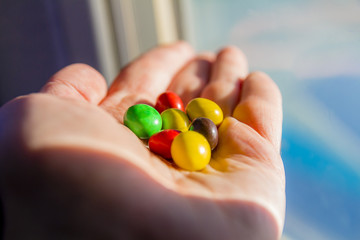 Man hand holding colorful chocolate candies buttons
