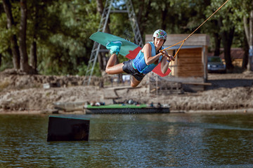 Fototapeta na wymiar Summer sports wakeboarding, water skiing on the board, jumps and tricks.