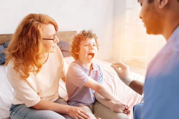 Serious pediatrician doing throat checkup