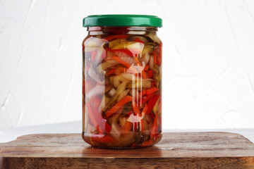 Jar with variety of pickled vegetables. Carrots, field garlic, cucumber in glas. Preserved food