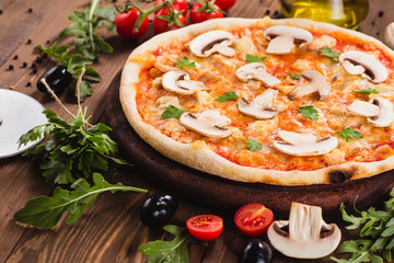 italian pizza with chicken and mushrooms on the wooden dark background (close).