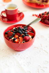 Healthy breakfast: cottage cheese with sour cream, strawberry, raspberry and blueberry, espresso, cherry cheesecake and plate of fresh ripe berries on white table cloth. Selective focus