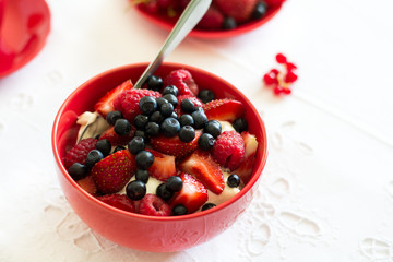 Healthy breakfast: cottage cheese with sour cream, strawberry, raspberry and blueberry, espresso, cherry cheesecake and plate of fresh ripe berries on white table cloth. Selective focus
