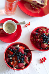 Healthy breakfast: cottage cheese with sour cream, strawberry, raspberry and blueberry, espresso, cherry cheesecake and plate of fresh ripe berries on white table cloth. Selective focus