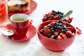 Healthy breakfast: cottage cheese with sour cream, strawberry, raspberry and blueberry, espresso, cherry cheesecake and plate of fresh ripe berries on white table cloth. Selective focus