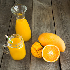 Obraz na płótnie Canvas Mango and orange juice and slice of orange on wooden table. Fresh healthy tropical drink.