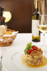 Moussaka arranged on a plate, Wine bottle and wineglass in background, Traditional dish in elegant setting, Selective focus with soft light