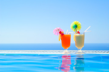 Two Colorful Tropical Cocktails near the Swimming Pool on Background of Warm Blue Sea. Exotic Summer Vacation.