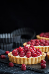 Delicious raspberry mini tarts on dark background