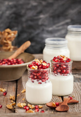Fresh yogurt with pomegranate seeds and walnut in a glass jars